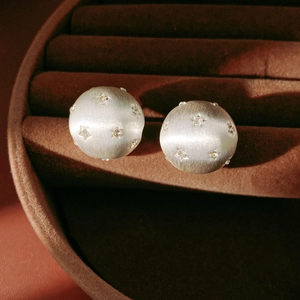 Gros plan de boucles d'oreilles en argent brossé avec délicates incrustations d'étoiles