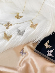 Detailed view of 14k gold butterfly pendants with colorful zircon on silk and fur background