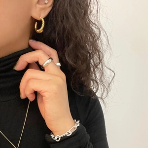 Set of twisted gold earrings, silver rings and chain bracelet worn by a fashion model