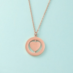 Detail of rose gold spinning heart pendant necklace on light blue background
