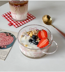 Detail of a clear glass bowl with pink bow print, filled with yogurt and fresh berries