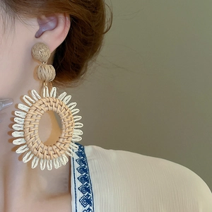 Gros plan détaillé des boucles d'oreilles bohèmes tressées en forme de pétale sur modèle