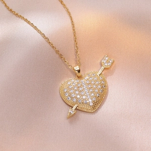 Gouden hartketting met pijlontwerp en zirkonia op zijden achtergrondstof