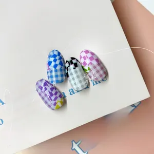 Vista macro di eleganti adesivi per unghie a scacchi in blu, nero, rosa e viola