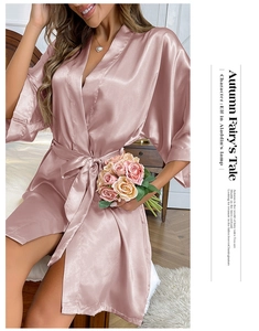 Macro detail of silky pink satin bathrobe showing smooth texture and v-neck design