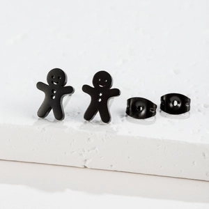 Detail of matte black gingerbread man stud earrings on white textured stone base