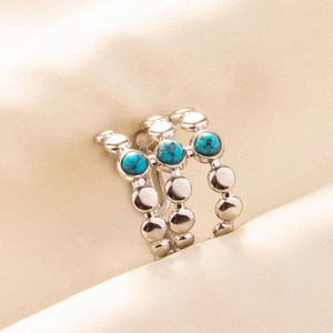 Macro view of triple-layered silver steel ring featuring turquoise stones on a fabric base