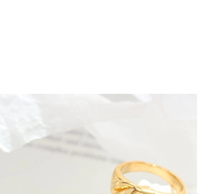 Détail macro d'une bague nœud plaquée or 18k avec design torsadé sur tissu blanc
