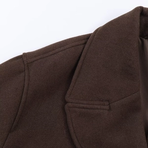 Detailed close-up of the notched lapel and shoulder seams on a brown wool short coat