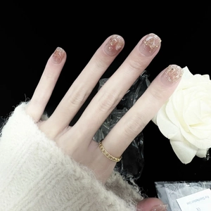 Elegante künstliche Nägel mit Goldglitzer-Verlauf an einer Hand mit weißer Rose