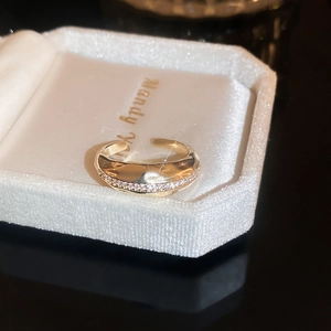 Close-up of gold open ring with row of white zircons in white velvet jewelry box