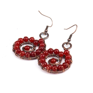 Detailed view of handmade wire-wrapped spiral earrings with red natural stone beads