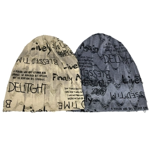 Detailed view of distressed knit beanies with ripped holes and letter printed patterns
