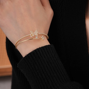 Close-up of double-layer gold bangle with zircon butterfly and clover charms on wrist