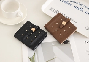 Detail of short PU leather wallets with quilted pattern and gold flower clasps