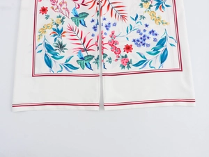 Detail of white wide-leg trousers featuring colorful floral prints and smooth fabric texture