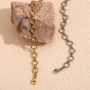 Detail of 14K gold and silver stainless steel chain anklets with lobster clasps on rock