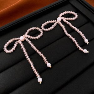 Detail of pink crystal beaded tassel earrings with bow design and white pearls