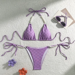 Detail view of purple checkered bikini featuring white pearl straps on soft plush background