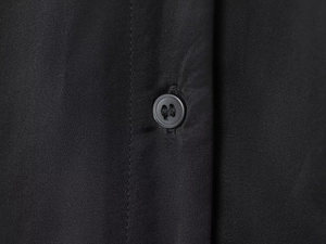 Close-up of fine woven black fabric texture with a matching four-hole button detail