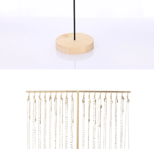 Detail showing gold metal T-bar necklace stand with hooks and natural wood base