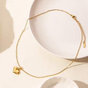 Close-up of golden heart pendant necklace with adjustable chain on a clean white surface