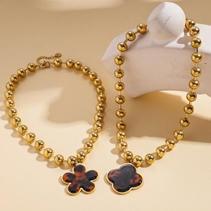 Vintage gold bead necklace with tortoise shell flower pendants on beige background