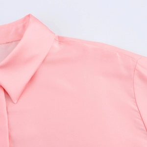 Gros plan du col d'un chemisier en satin rose montrant le tissu soyeux et les coutures