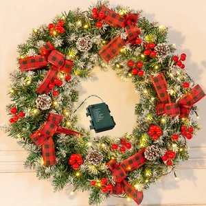 Close-up of snow-flocked Christmas wreath with berries, cones and LED battery controller