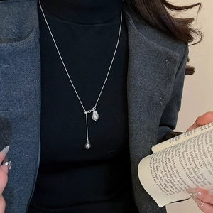 Detail of silver pea pendant pearl necklace on model in elegant business attire