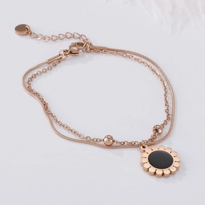 Detail of rose gold double-layered bracelet with daisy pendant and lobster clasp closure