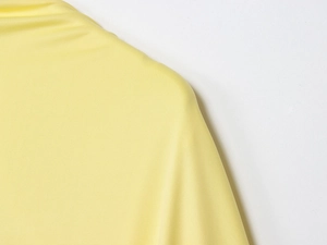 Close-up of yellow knit fabric detail showing backless layered dress shoulder texture