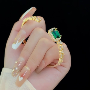 Detail of emerald green zircon gold bangle with micro-pave stones on black background