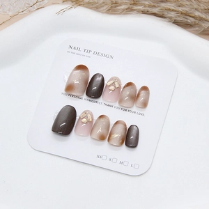 Handmade press-on nails set with brown cat eye effect and glitter stones on white display