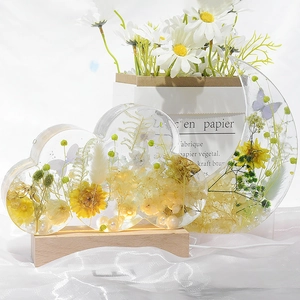 Detailed view of handmade resin moon and cloud bookends with dried flowers and wood base