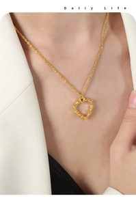 Détail d'un pendentif cœur doré irrégulier à texture de lave sur une chaîne torsadée