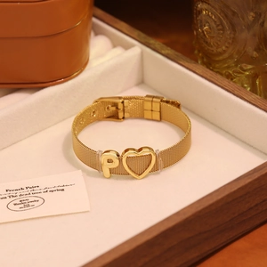 Gros plan du bracelet en maille dorée avec charm en cœur et détail de la lettre P