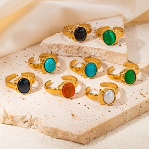 Detail of adjustable gold rings with various oval natural stones on stone textures