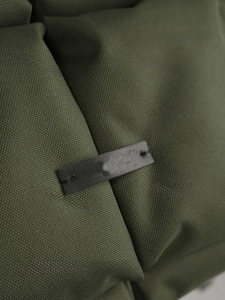 Gros plan sur la toile imperméable vert foncé et l'écusson décoratif en cuir noir du sac