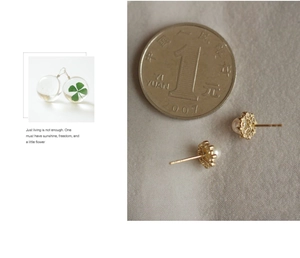 Close-up of golden hollow pearl earrings and floral glass studs next to a coin for scale