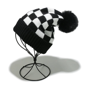 Winter beanie with black and white checkerboard pattern and large faux fur pom-pom