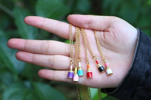 Close-up of assorted colorful lipstick pendants with crystal accents on gold chain