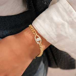Détail du bracelet œil protecteur doré avec zircons brillants au poignet féminin