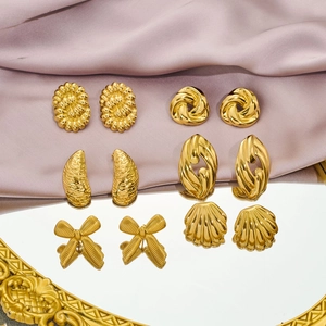 Detailed view of six pairs of gold bow and textured earrings on silk background