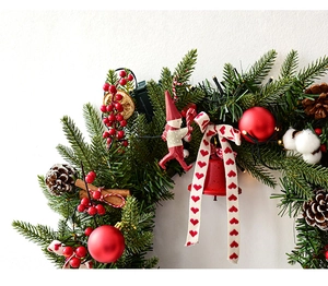Detail van Noordse kerstkrans met dennennaalden, rode bessen en zacht katoen decor