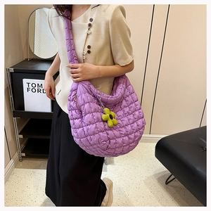 Close-up of purple quilted puff tote bag featuring a yellow flower charm accessory