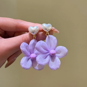 Close-up of purple fabric flower earrings with heart pearl studs for vacation style