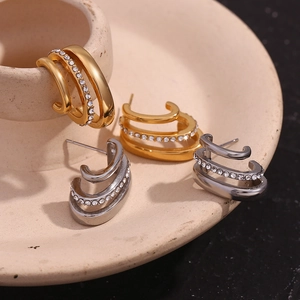 Close-up of three-row C-shaped gold and silver earrings with sparkling rhinestones