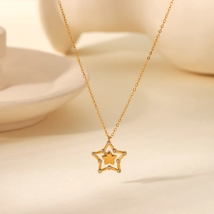 Detail of gold necklace featuring a double star pendant with crystal pavé and polished finish