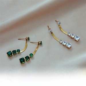 Detail of gold blade chain earrings with square emerald and clear cubic zirconia stones